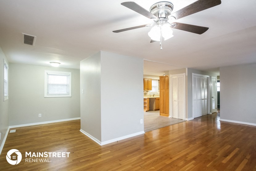 the living room and dining room with wood flooring and a ceiling fan
