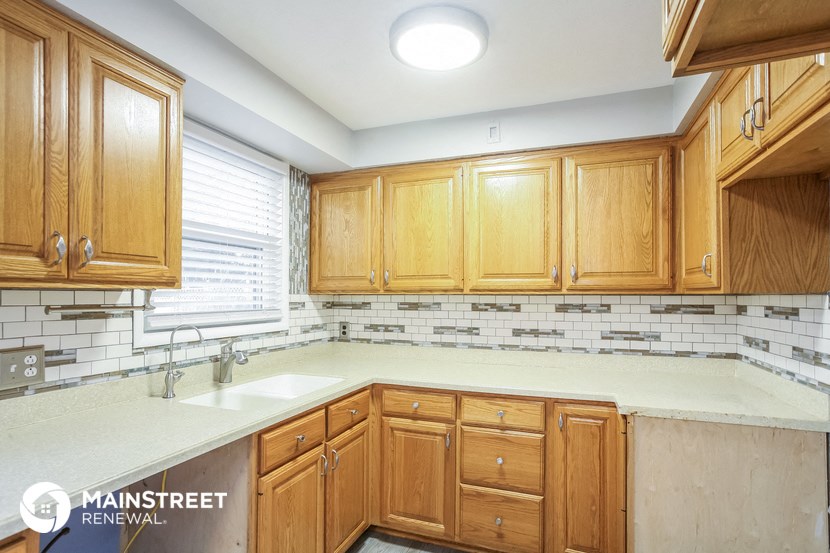 a kitchen with wood cabinets and white counter tops and a sink