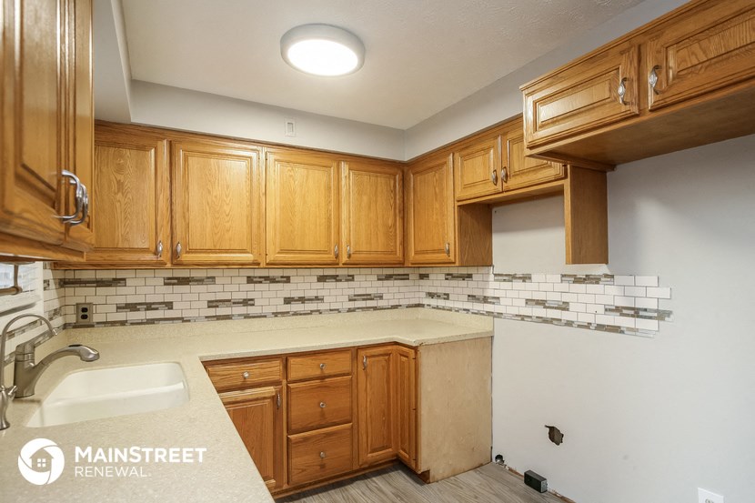 a kitchen with wood cabinets and white counter tops and a sink
