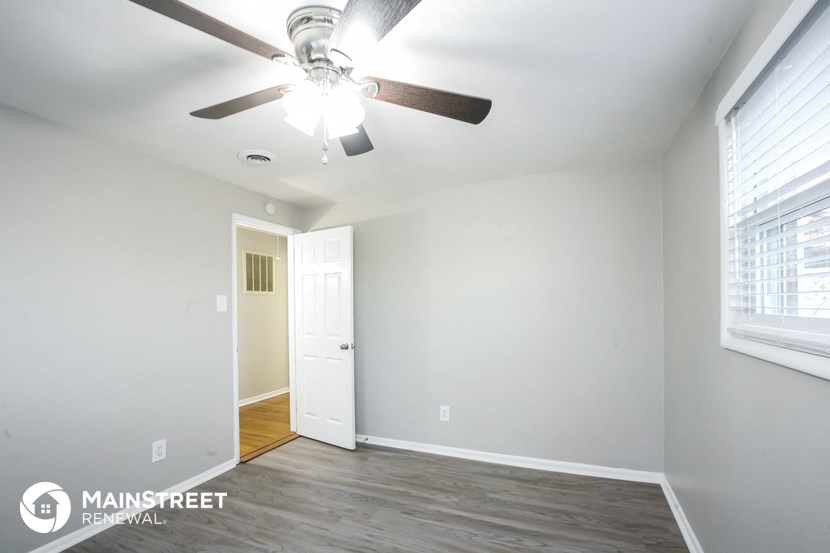 a living room with a ceiling fan and a door to a hallway