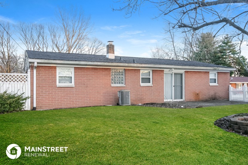 a small brick house with a yard and a white fence