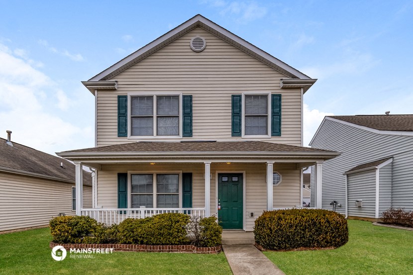 a tan house with green shutters and a green door