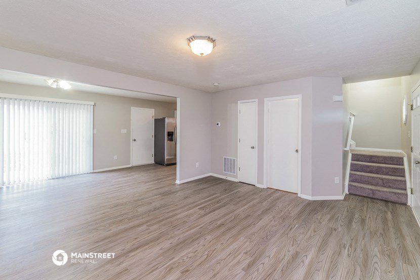 the living room of an apartment with a hardwood floor and a staircase