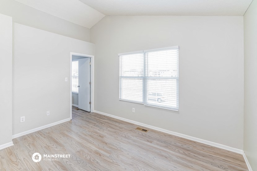 the spacious living room with wood flooring and a large window