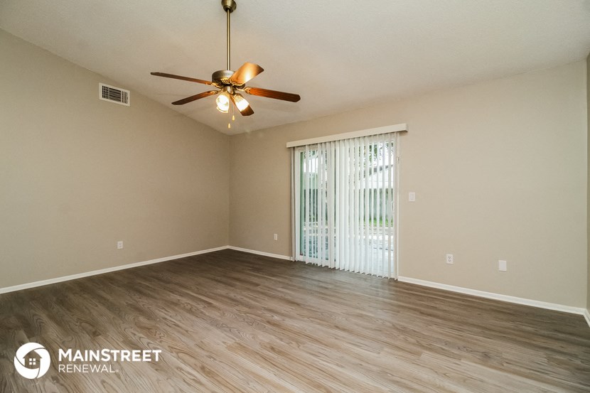an empty living room with a ceiling fan and a window
