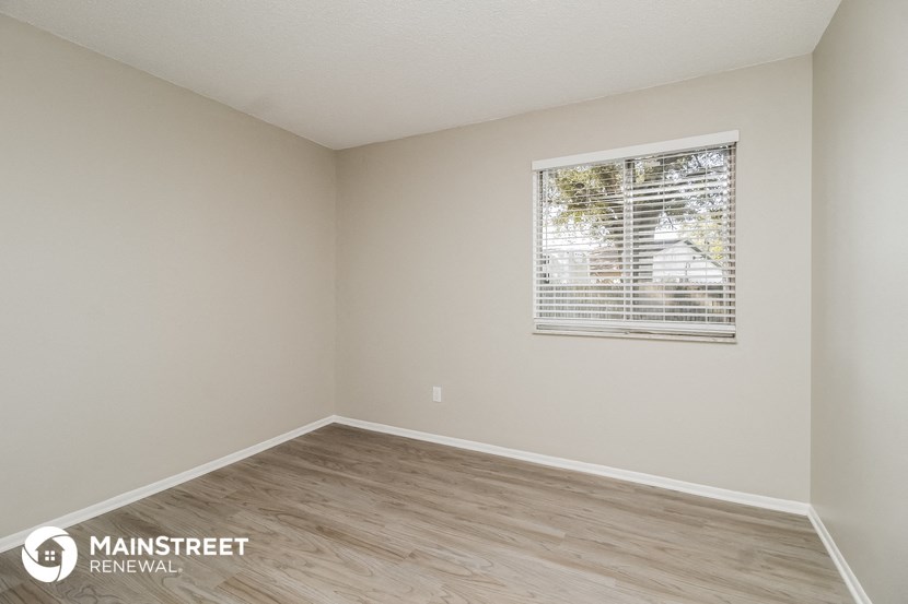 the spacious living room with wood flooring and a window