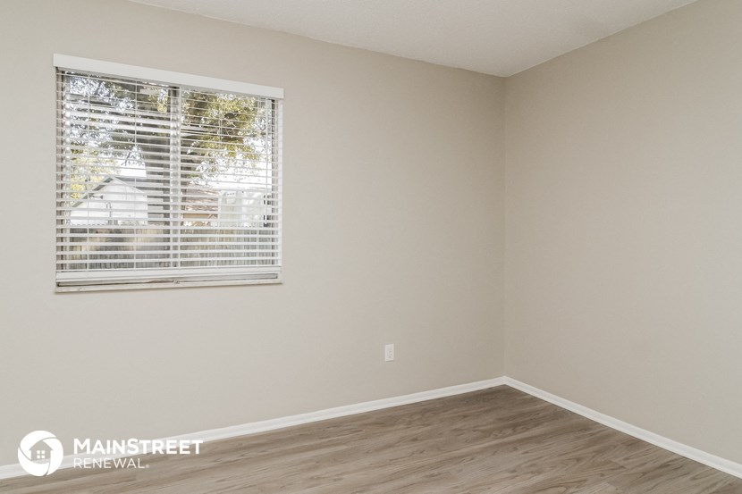 the living room of an apartment with a window and wooden floors