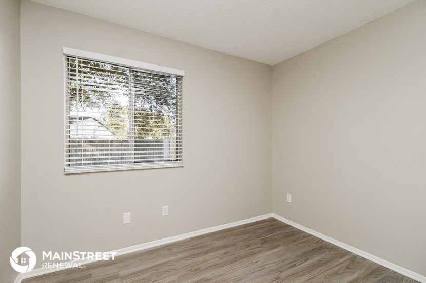 the spacious living room with a large window and wood flooring