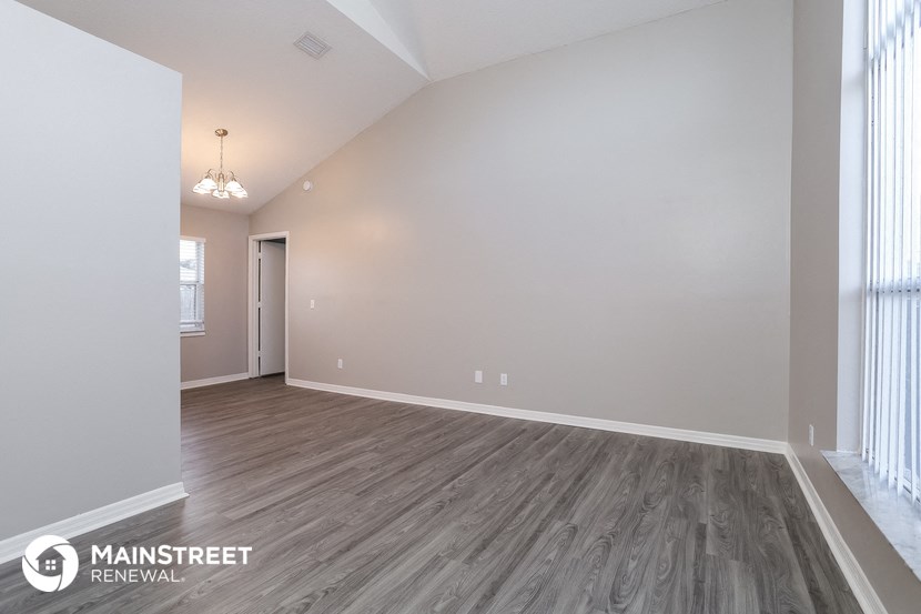 the spacious living room with wood flooring and white walls