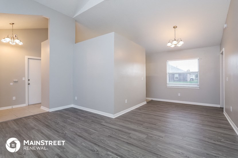 the spacious living room with wood flooring and white walls
