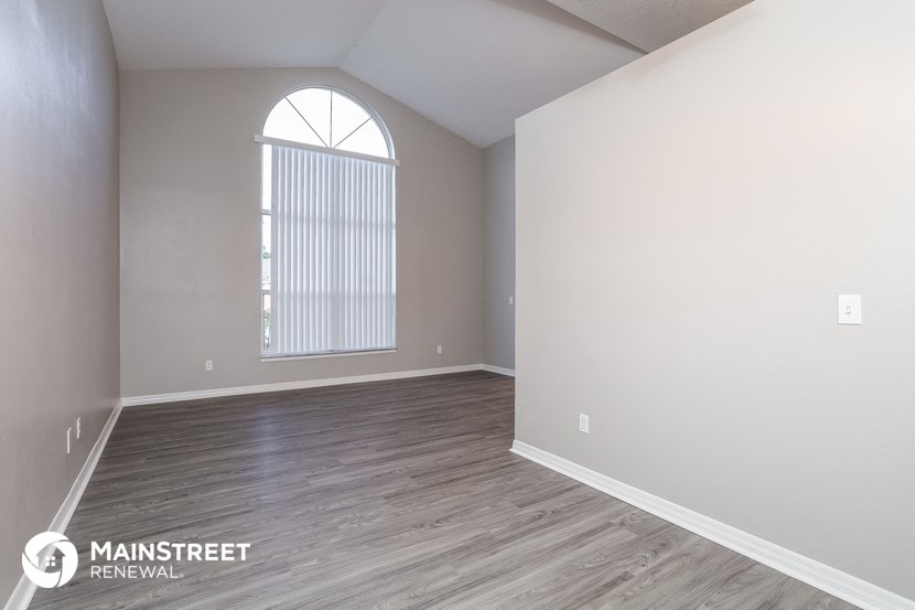 the spacious living room with wood flooring and a large window