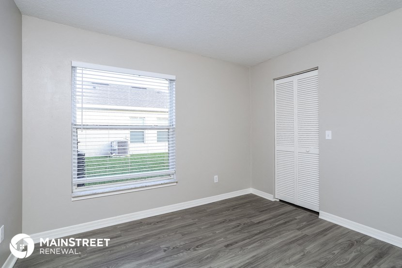 the living room of an apartment with a window and wood flooring