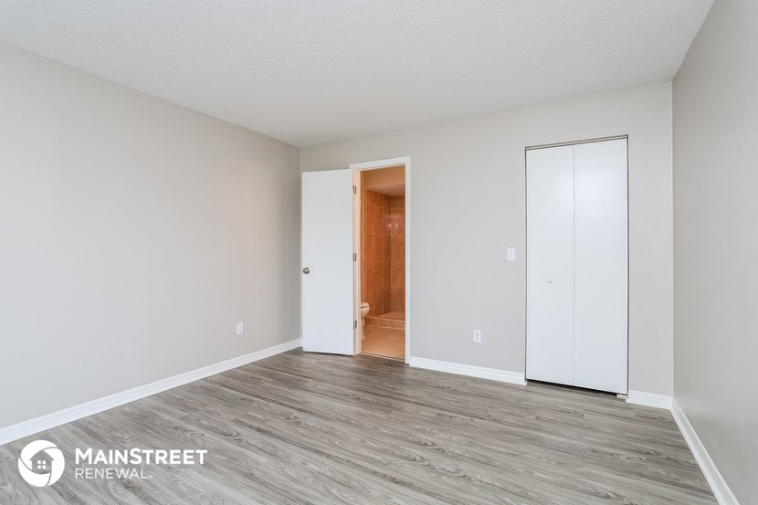 the spacious living room with white walls and wood flooring