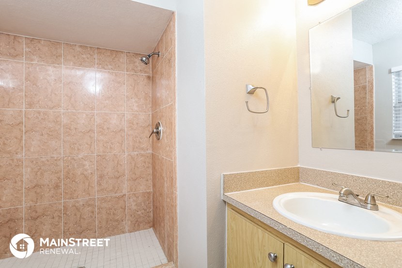 a bathroom with a sink and a shower and a mirror