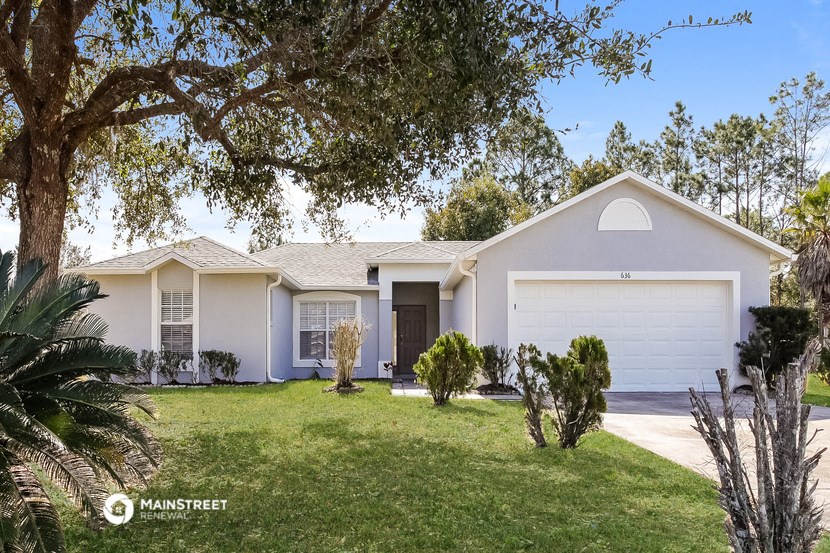 a white house with a lawn and a tree