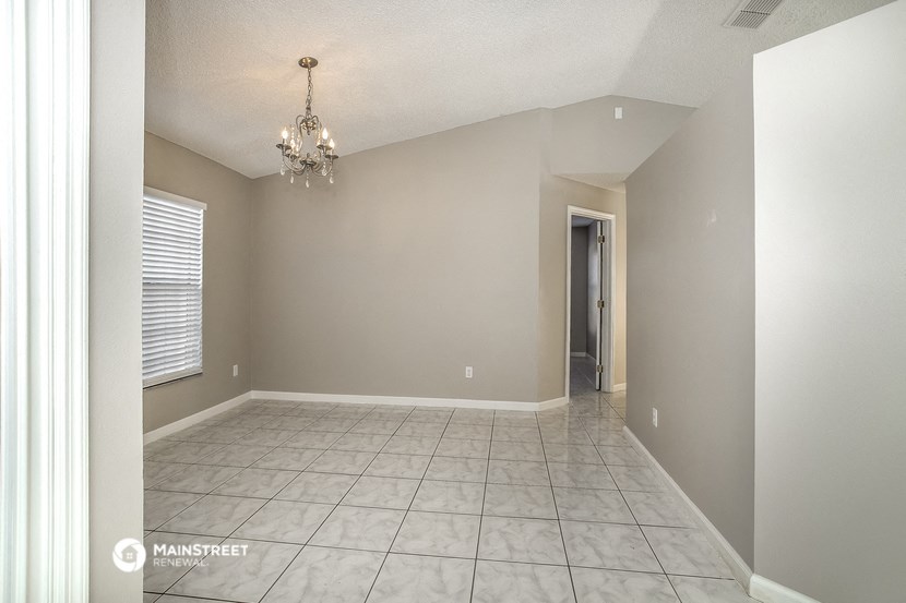 the spacious living room with a chandelier and tiled floor