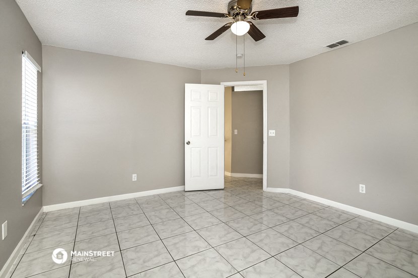 an empty living room with a ceiling fan and a white door