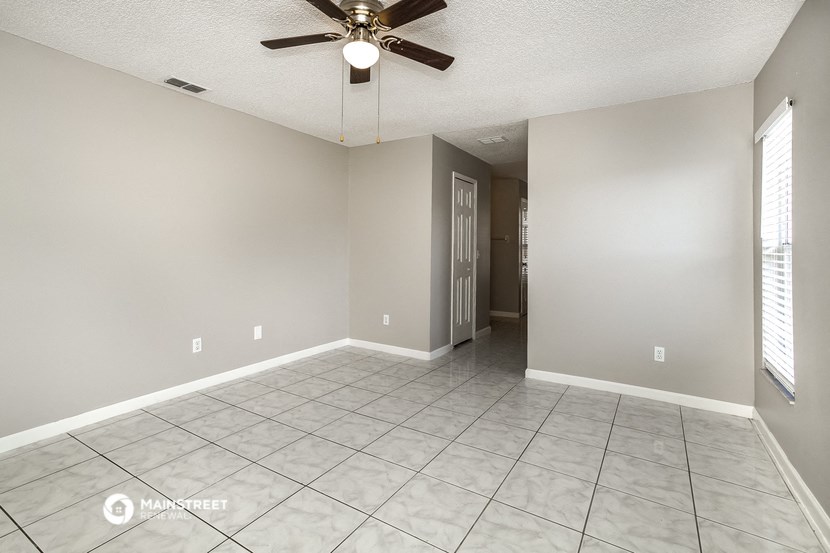 the spacious living room with tile flooring and a ceiling fan