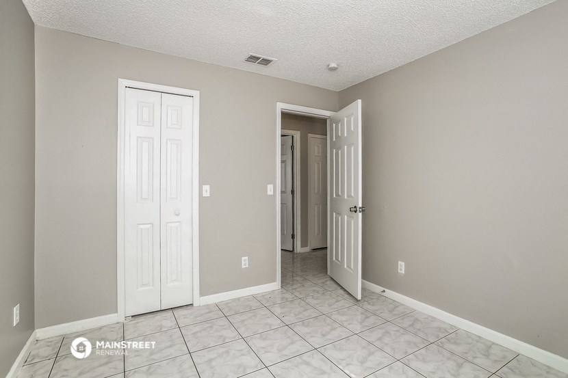 the living room of an apartment with two doors and a tiled floor