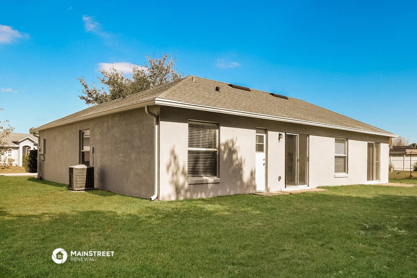 a small gray house with a grass yard and a blue sky