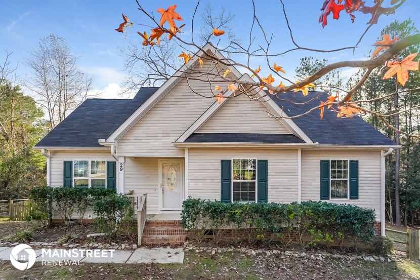 a white house with green shutters and a tree with autumn leaves