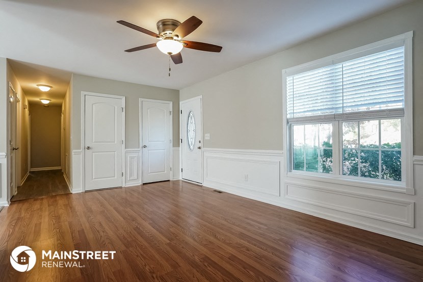 an empty living room with a ceiling fan and a window