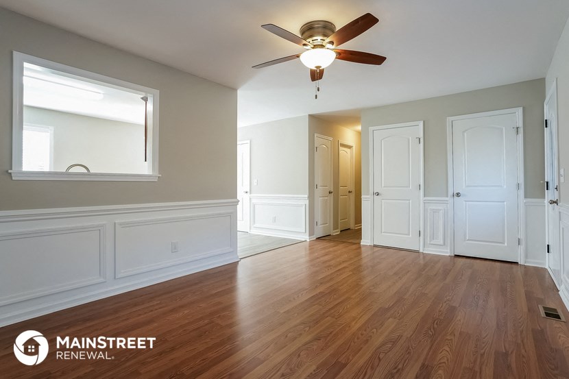 an empty living room with wood floors and a ceiling fan