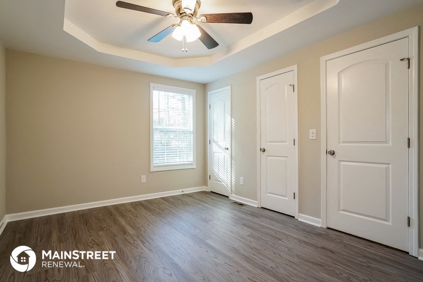 an empty living room with a ceiling fan and two doors