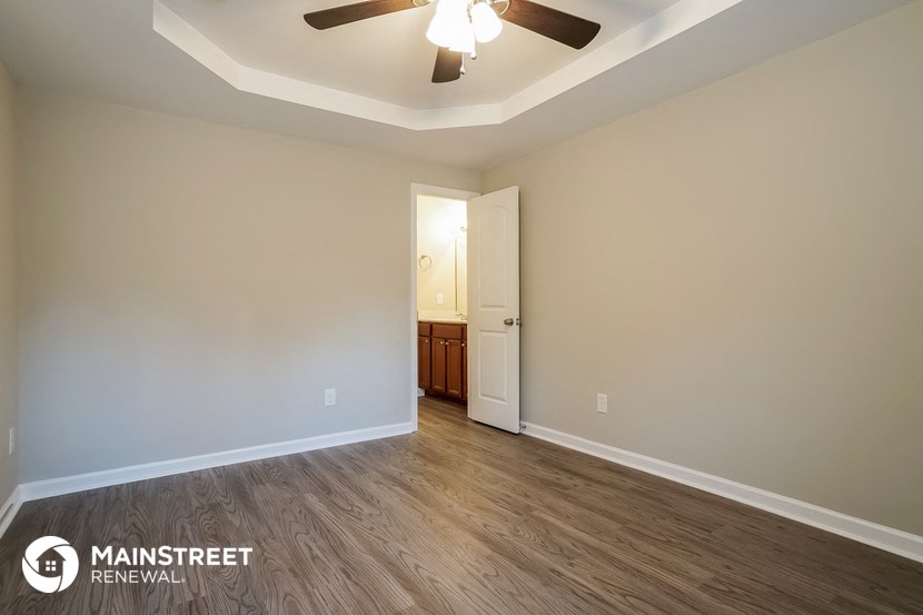 an empty living room with wood flooring and a ceiling fan