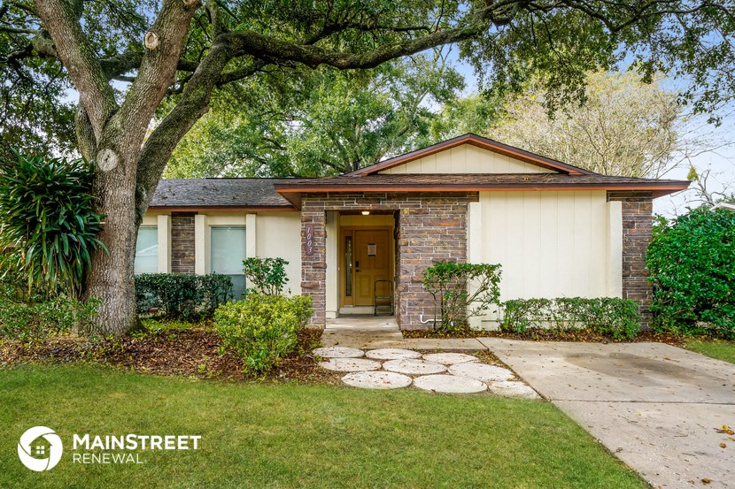 a small brick house with a sidewalk and a tree