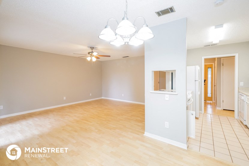 the living room and dining room with wood floors and a ceiling fan