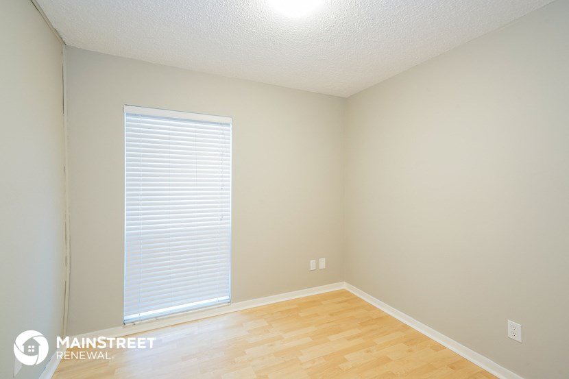 a room with a wood floor and a large window with a window blinds