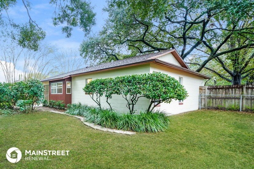 a small white house with a lawn and trees