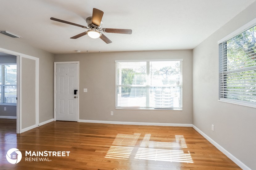 an empty living room with a ceiling fan and a window