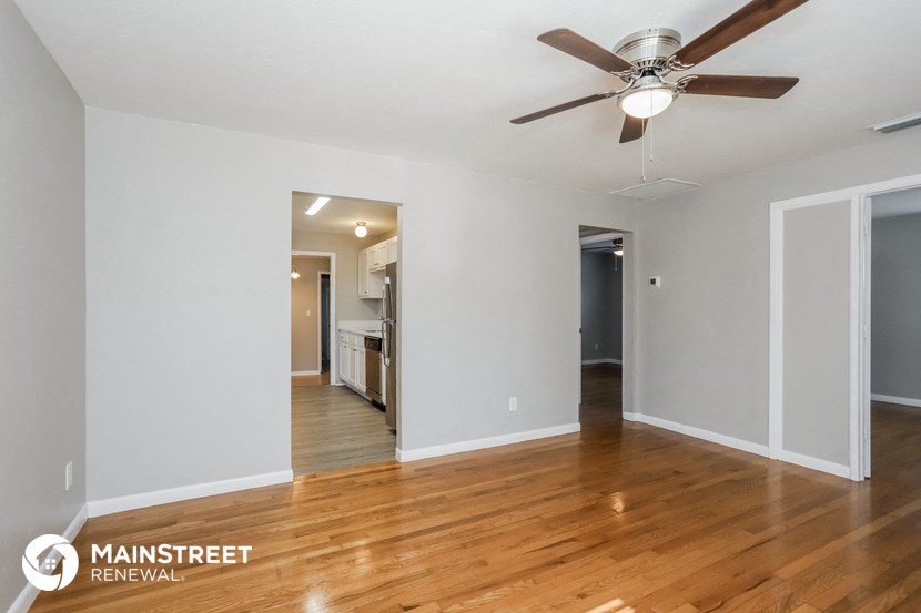 the living room and dining room with wood flooring and a ceiling fan