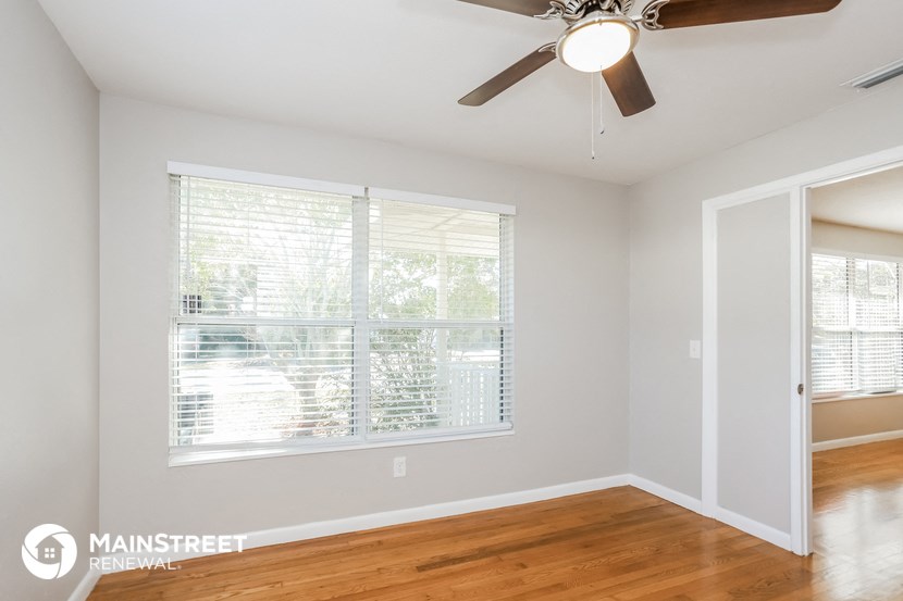 a living room with a large window and a ceiling fan