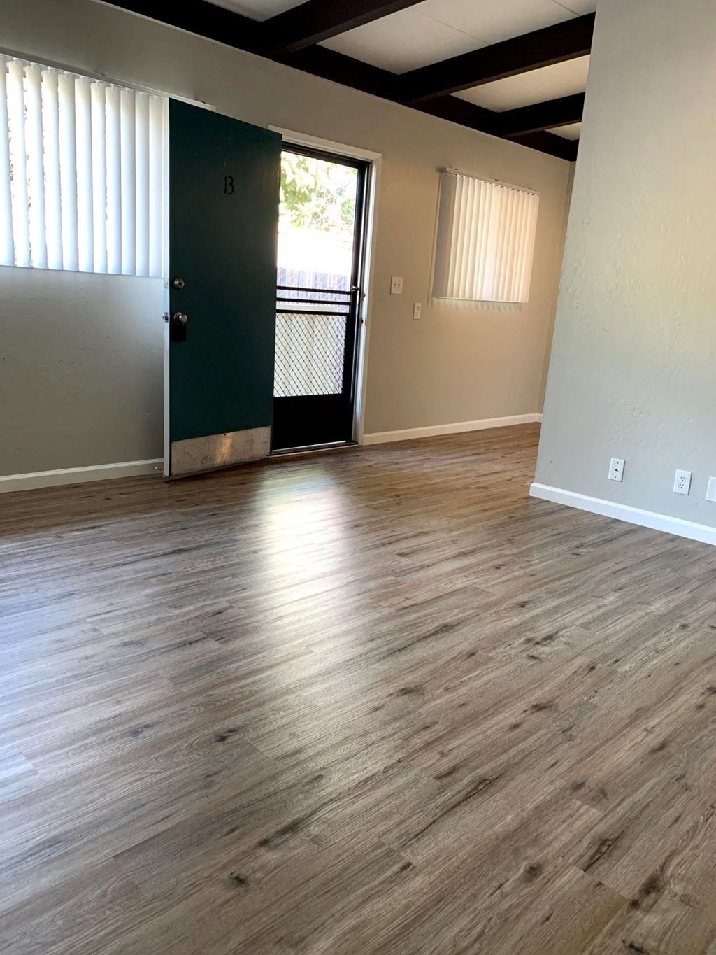 an empty living room with wood floors and a door to a balcony