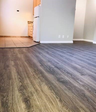 a living room with a refrigerator and a wooden floor