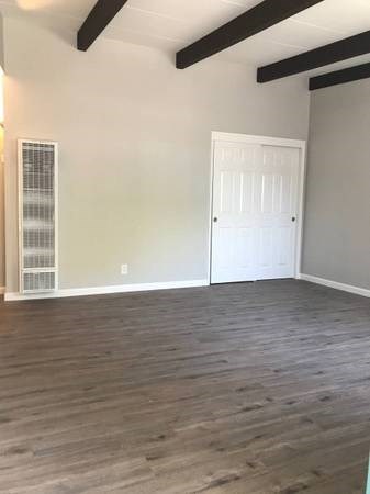 an empty living room with wood floors and a white door