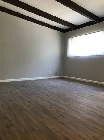 an empty room with wooden floors and a window