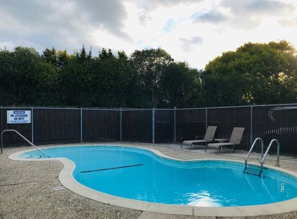 a blue swimming pool with two chairs and a fence