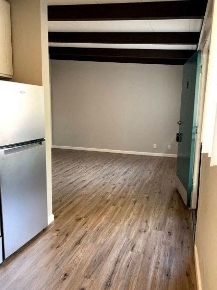 an empty room with a refrigerator and wooden floors