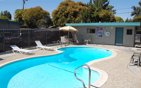 a resort style swimming pool with chairs and an umbrella