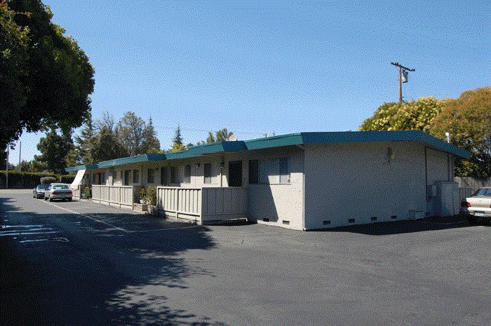 a motel with a parking lot and a building with a green roof
