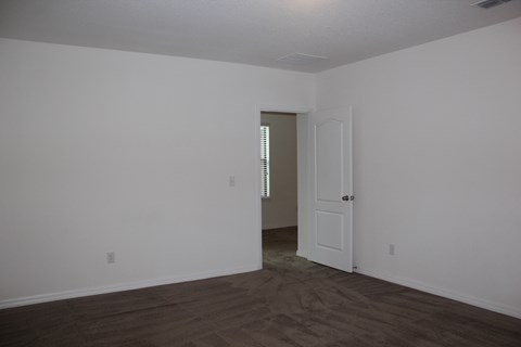 a bedroom with white walls and a door into a hallway