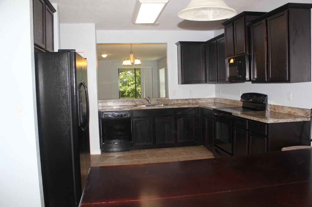 a kitchen with black cabinets and a black refrigerator