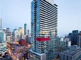 A tall building with a red signboard is the centerpiece of a bustling cityscape.