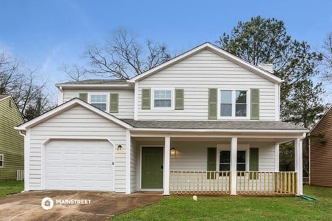 a white house with a porch and a green door