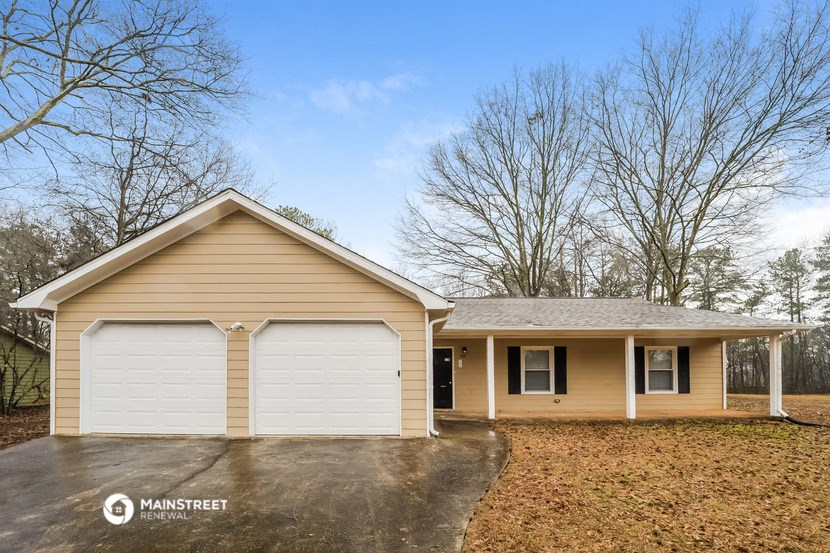 the front of a yellow house with a white garage door