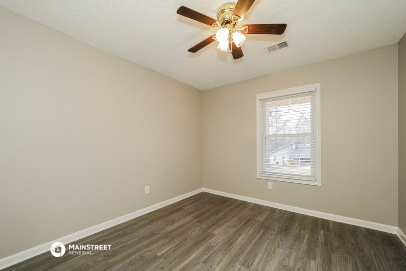 the spacious living room with wood flooring and a ceiling fan